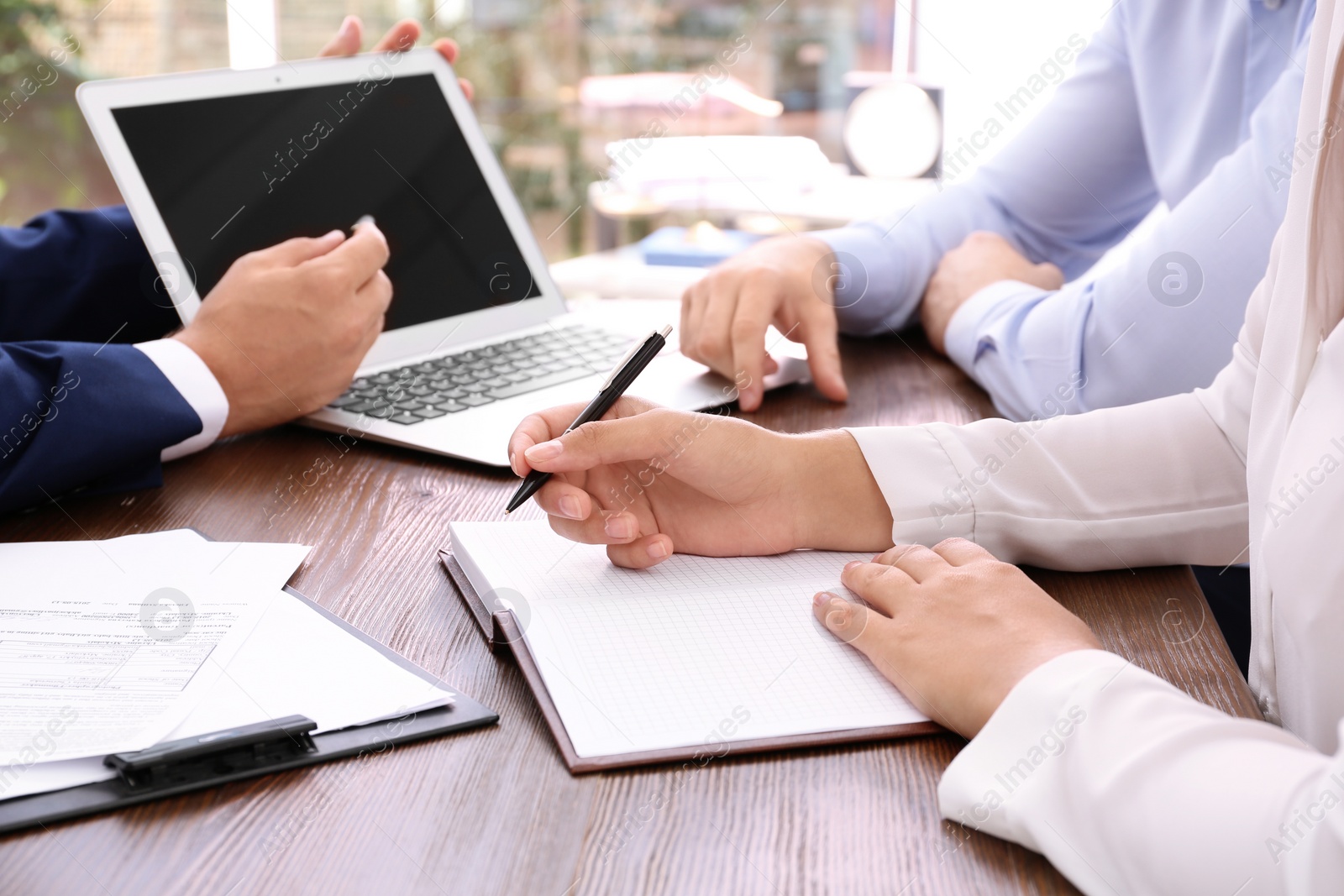 Photo of Lawyer working with clients at table in office, focus on hands