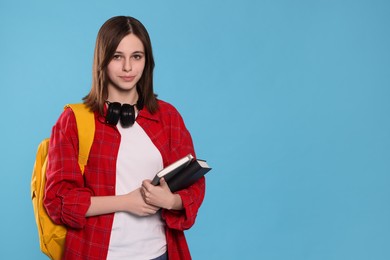 Photo of Portrait of beautiful teenage girl with books on light blue background. Space for text