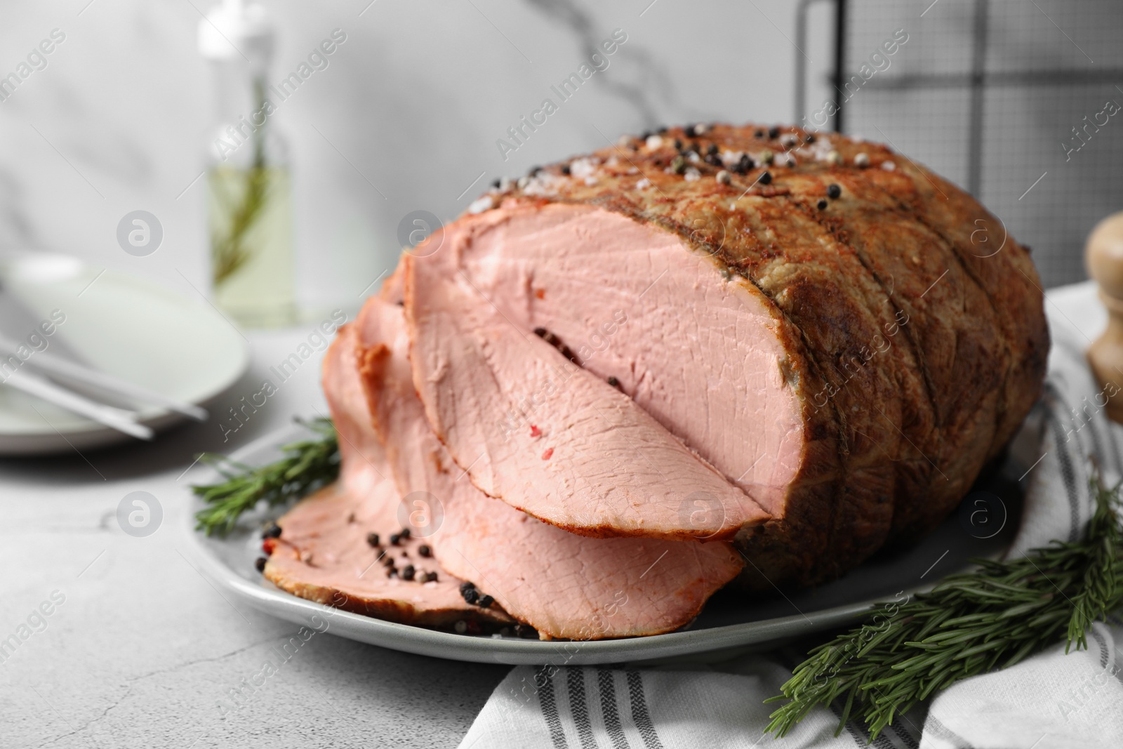 Photo of Delicious baked ham and rosemary on light grey table, closeup