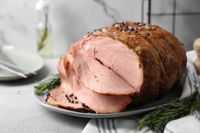 Delicious baked ham and rosemary on light grey table, closeup