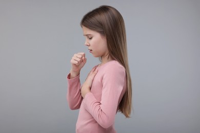 Photo of Sick girl coughing on gray background. Cold symptoms