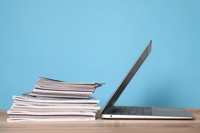 Laptop and stack of magazines on wooden table