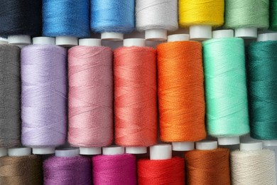 Photo of Set of different colorful sewing threads as background, top view