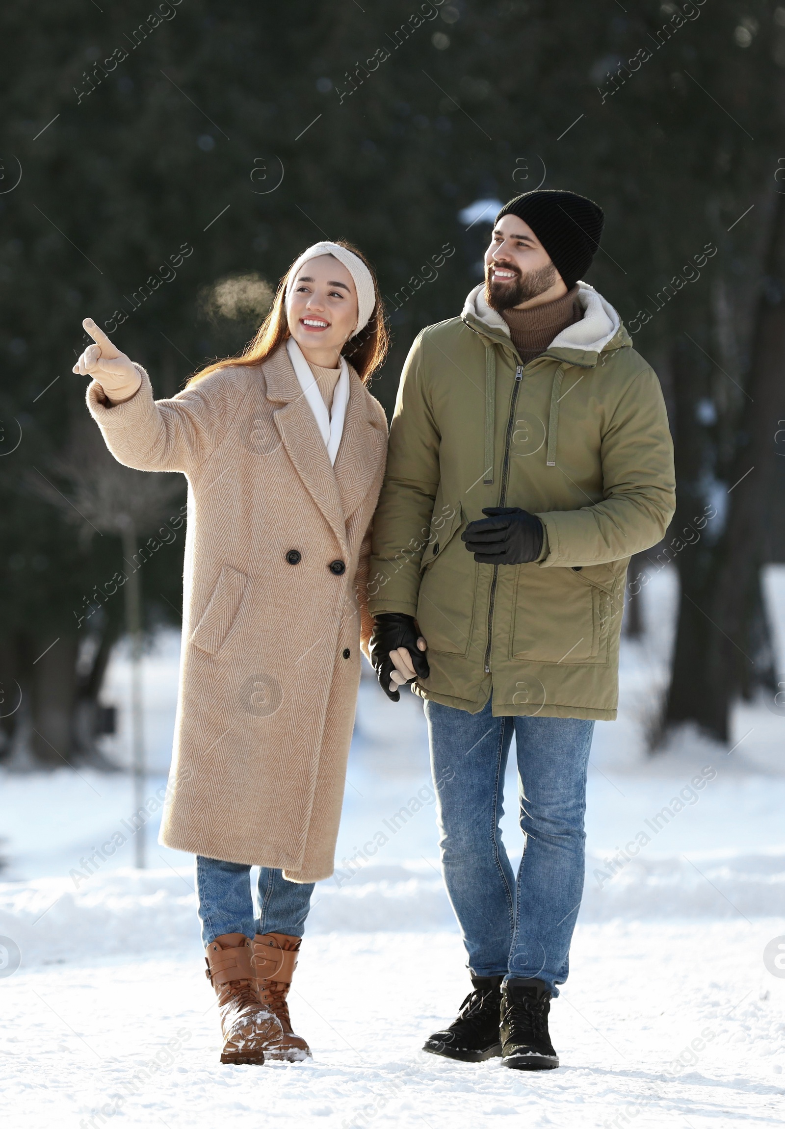 Photo of Happy young couple walking in snowy park on winter day