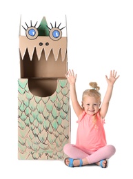 Photo of Cute little girl playing with cardboard dragon on white background
