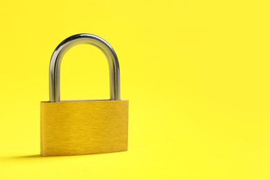 Photo of Steel padlock on yellow background. Space for text