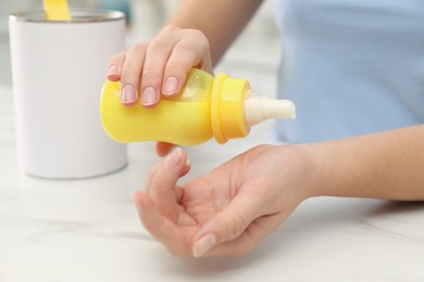 Photo of Woman checking temperature of infant formula at table indoors, closeup. Baby milk