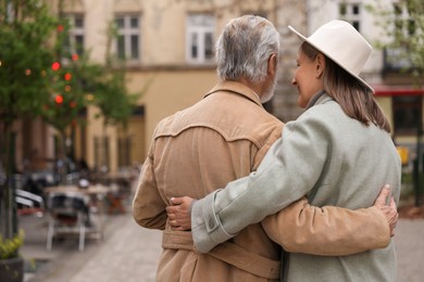 Photo of Affectionate senior couple walking outdoors, back view. Space for text