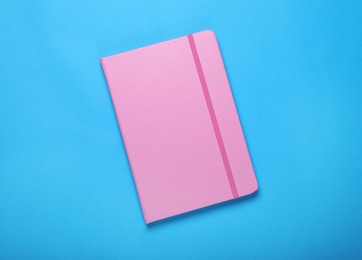 Photo of Pink notebook on light blue background, top view