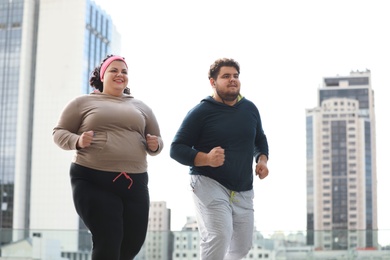 Photo of Overweight couple running together outdoors. Fitness lifestyle