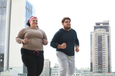 Overweight couple running together outdoors. Fitness lifestyle