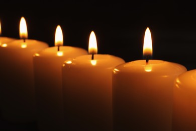 Photo of Burning candles on dark background, closeup. Memory day