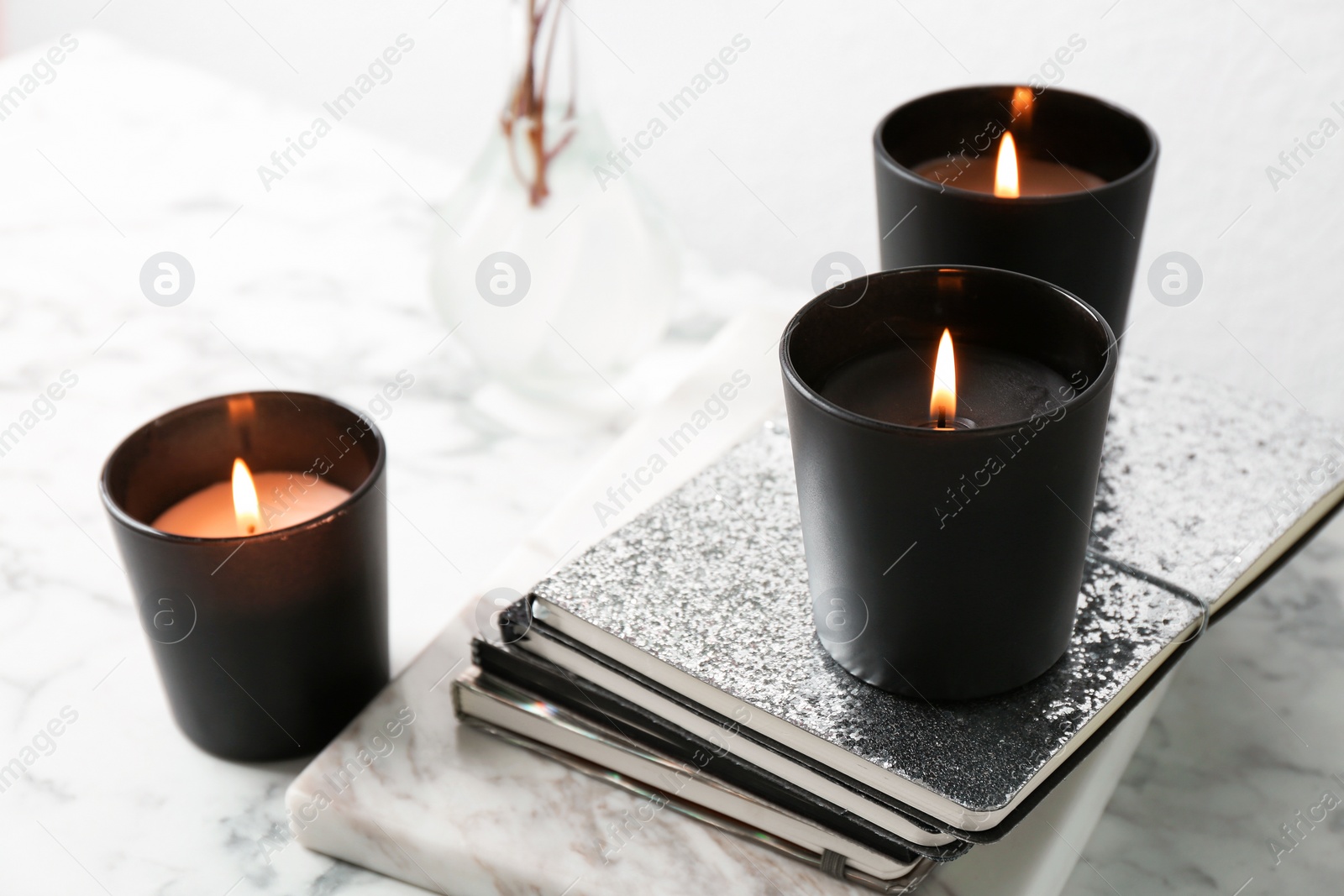 Photo of Burning candles and notebooks on table, space for text
