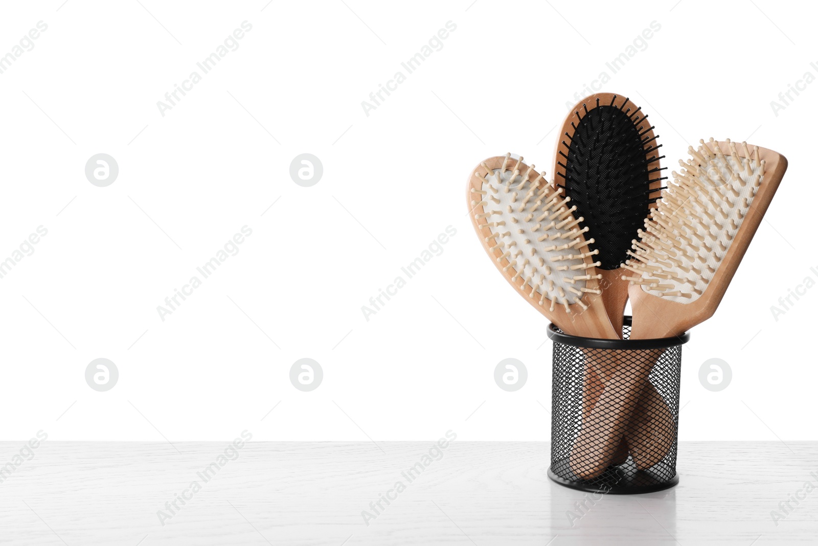 Photo of Modern hair brushes in holder on white wooden table