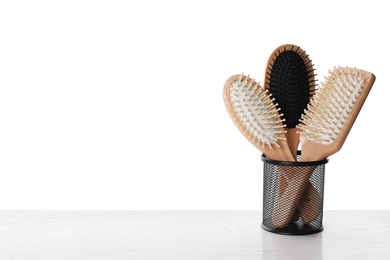 Photo of Modern hair brushes in holder on white wooden table