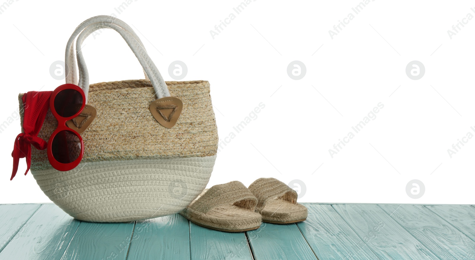 Photo of Stylish bag with beach accessories on light blue wooden table. Space for text