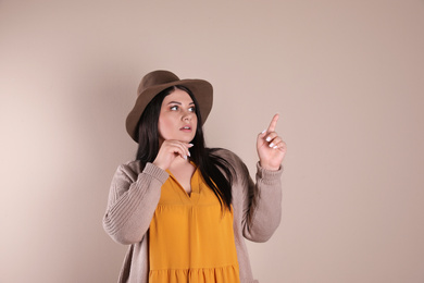 Photo of Emotional overweight woman posing on beige background. Plus size model