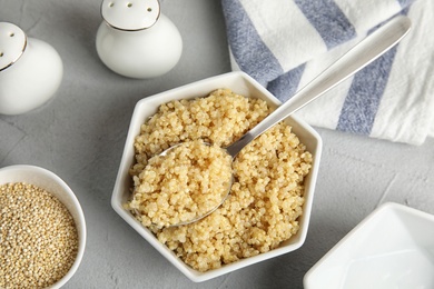 Composition with cooked quinoa in white ceramic bowl on table, top view