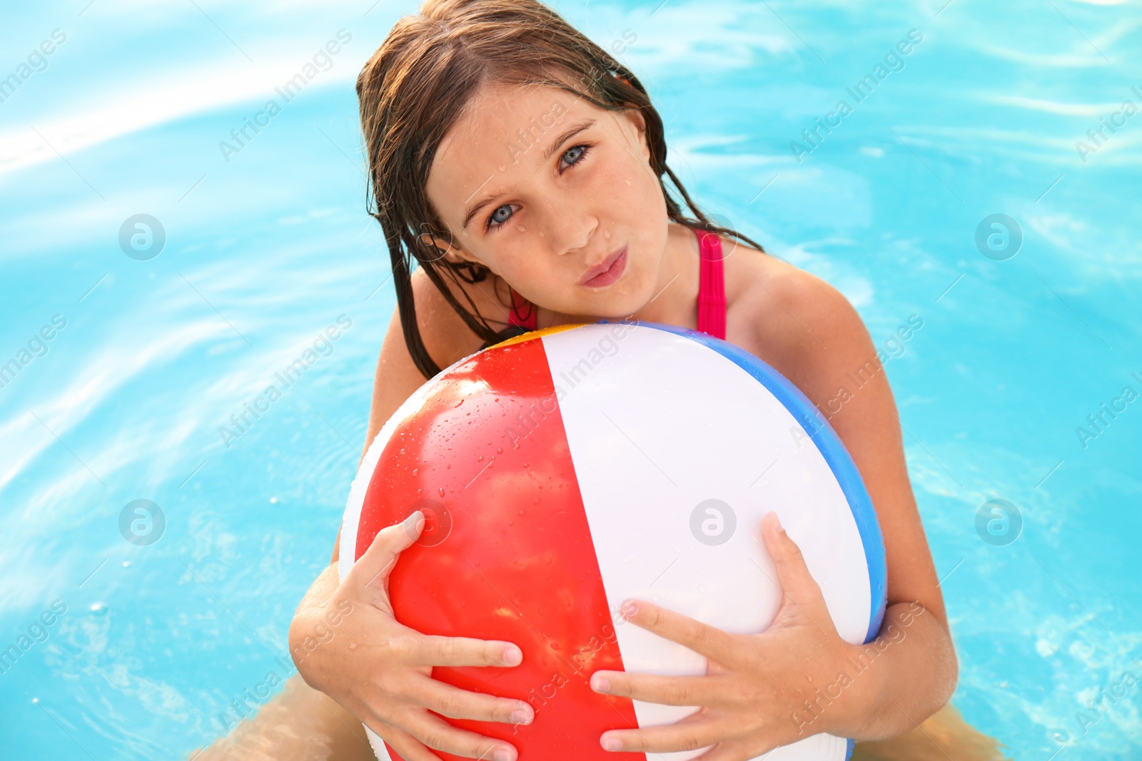 Photo of Happy cute girl with inflatable ball in swimming pool