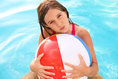 Happy cute girl with inflatable ball in swimming pool