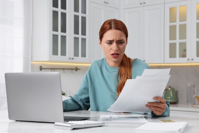 Photo of Woman doing taxes at table in kitchen