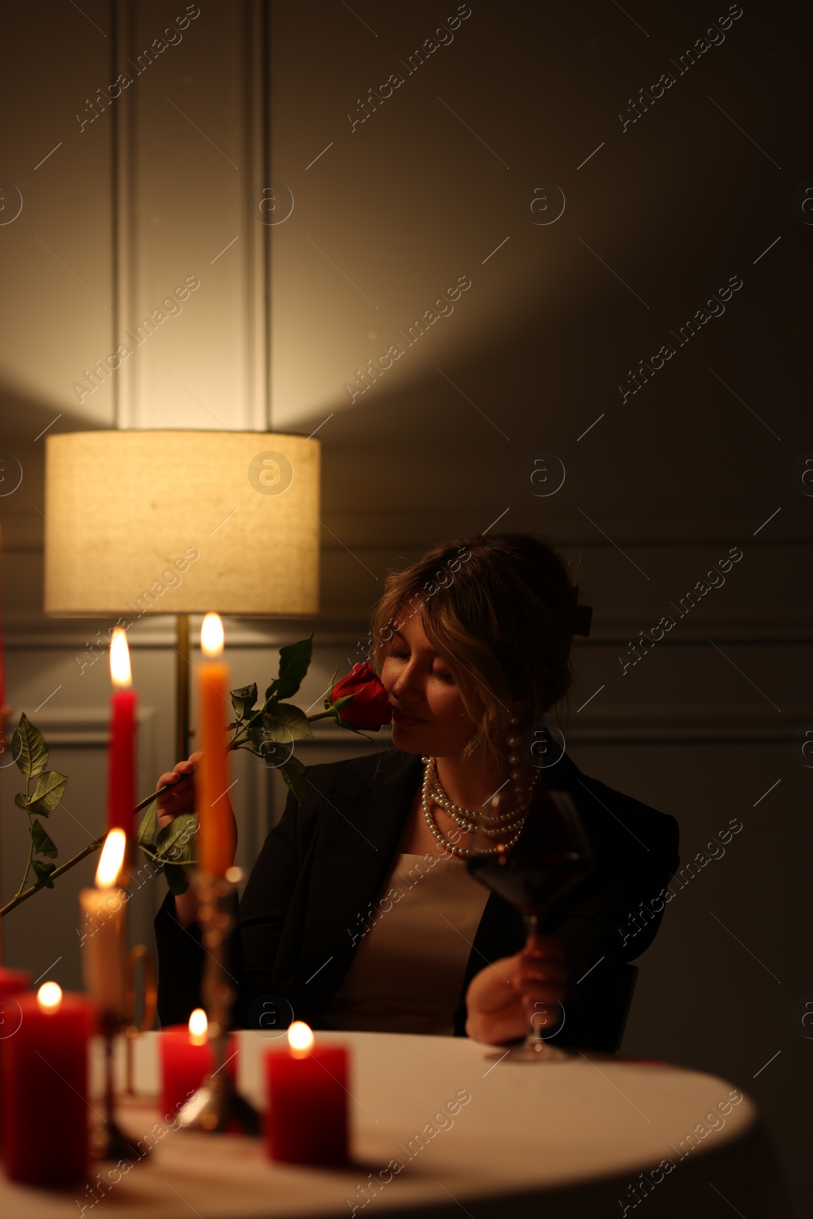 Photo of Beautiful young woman with glass of wine and rose at table in restaurant
