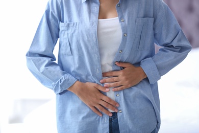 Photo of Young woman suffering from menstrual cramps on light background. Gynecological care