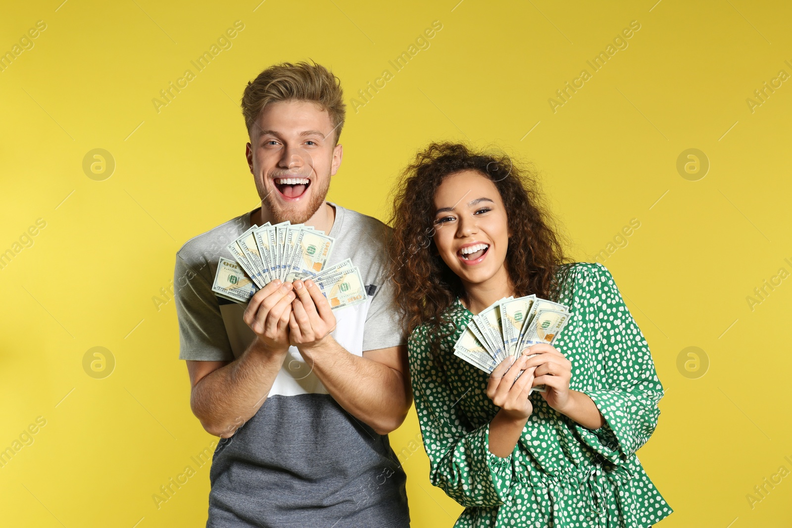 Photo of Young couple with money on color background