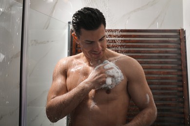 Photo of Man with mesh pouf taking shower at home