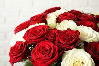 Luxury bouquet of fresh roses near white brick wall, closeup