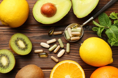 Photo of Different vitamin pills and fresh fruits on wooden table, flat lay