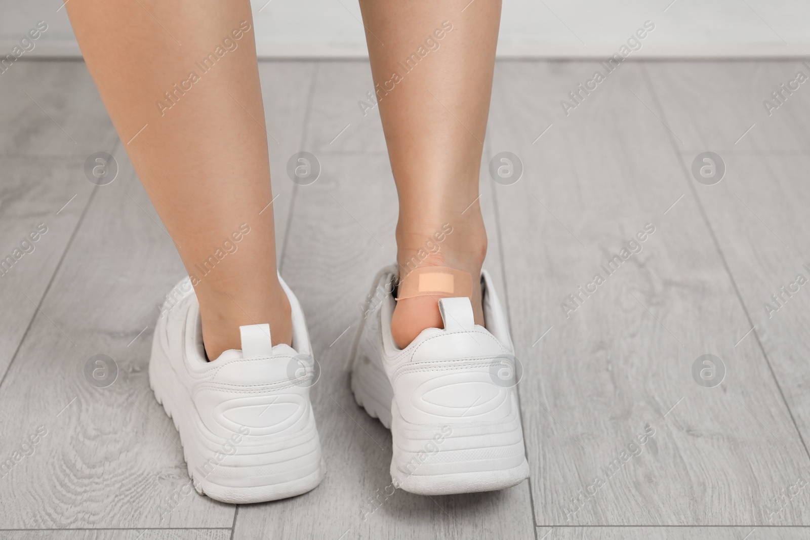 Photo of Female with plastered heel on wooden floor, closeup view. Space for text