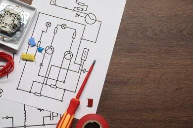 Wiring diagrams, wires and disassembled light switch on wooden table, flat lay. Space for text