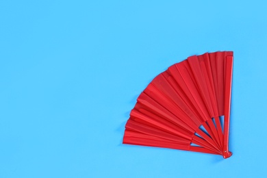 Photo of Red hand fan on light blue background, top view. Space for text