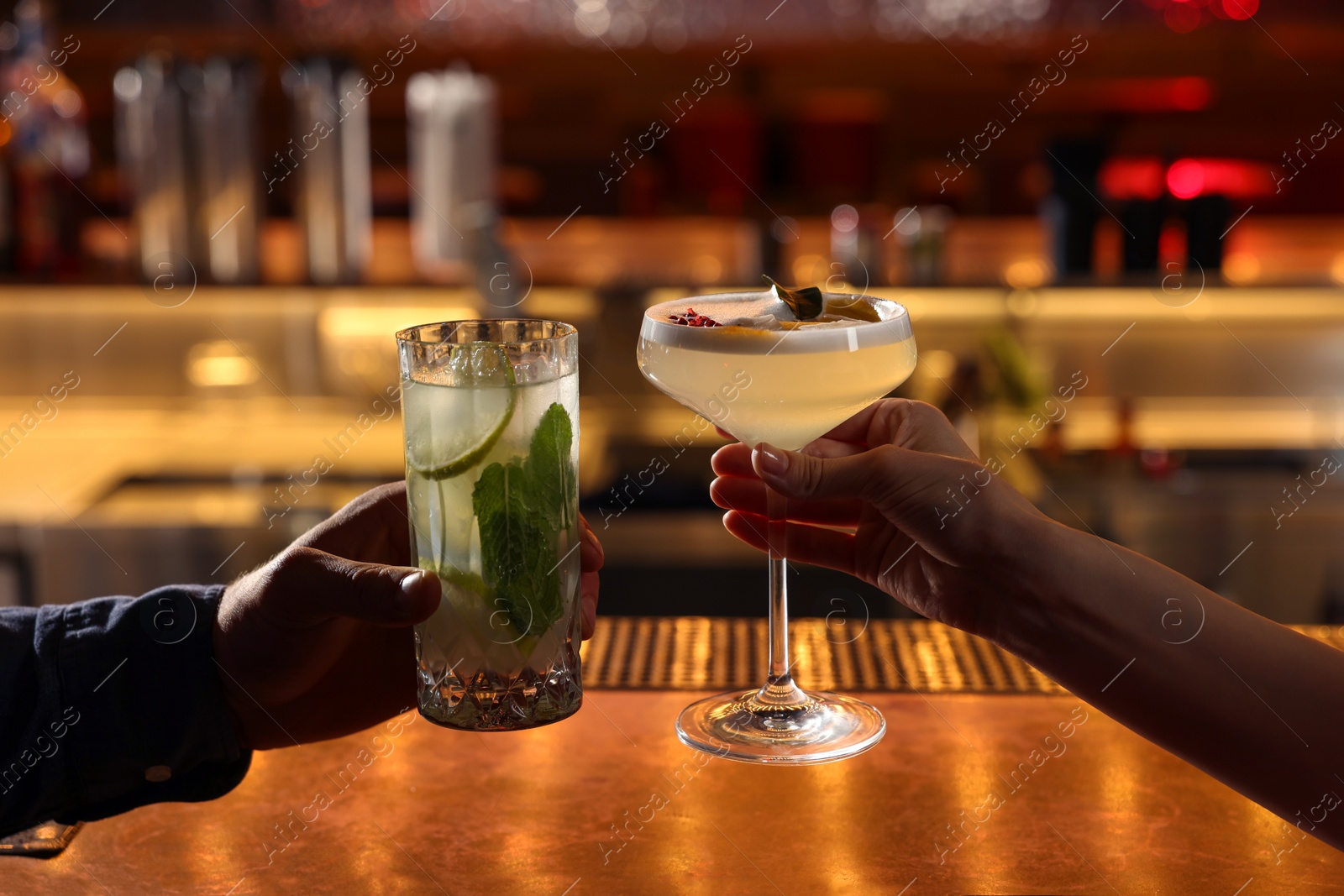 Photo of People holding glasses with fresh cocktails at bar counter, closeup