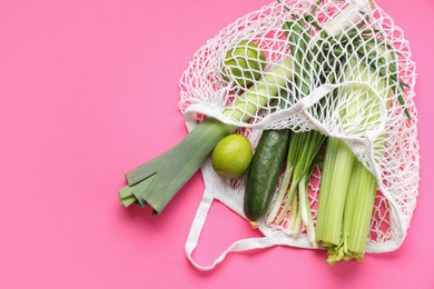 String bag with different vegetables on bright pink background, top view. Space for text