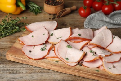 Photo of Delicious sliced ham with thyme and peppercorns on wooden table
