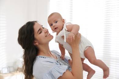 Happy young mother with her cute baby near window at home