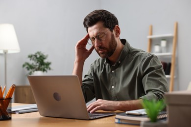 Tired man suffering from headache at workplace