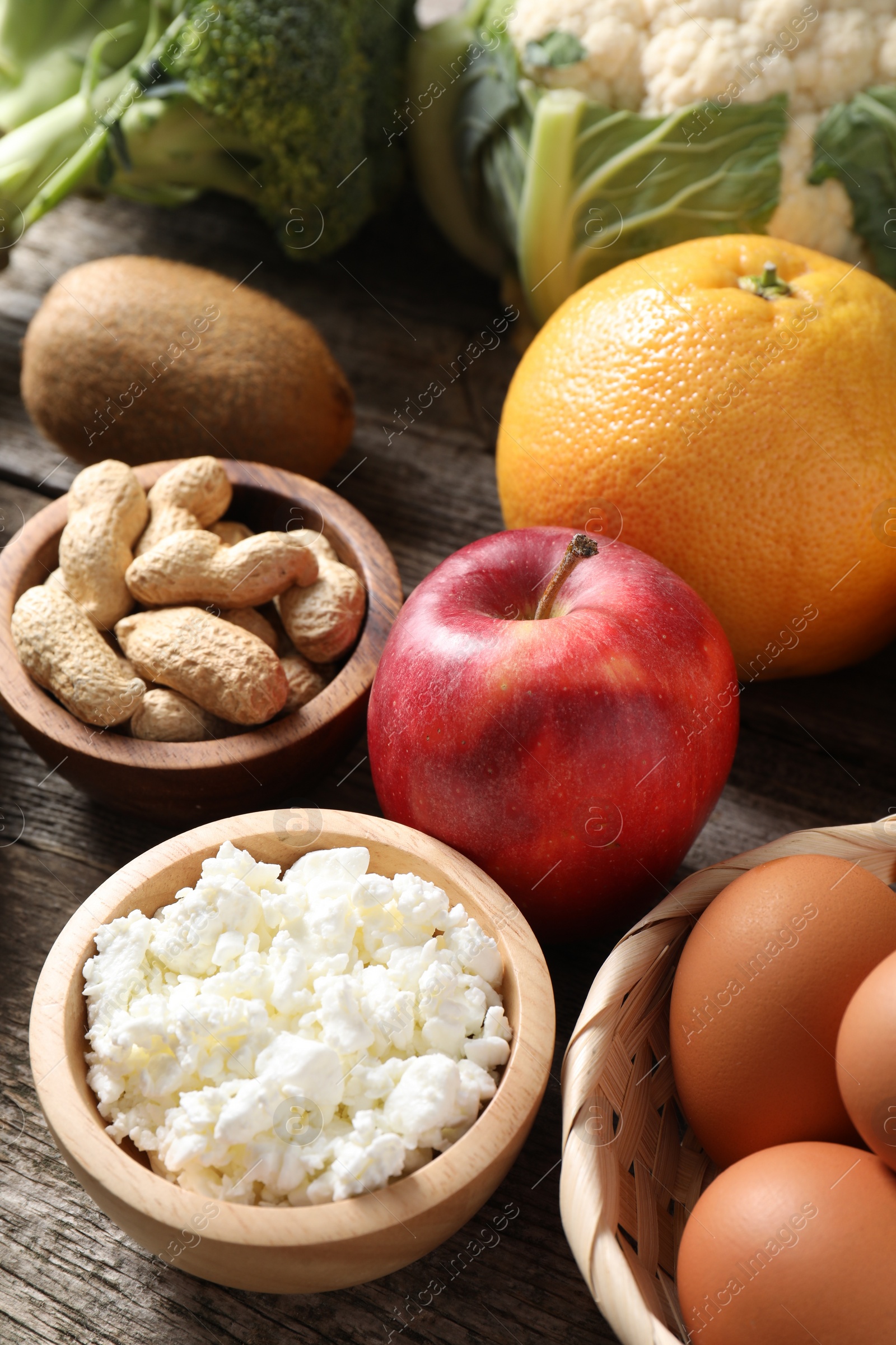 Photo of Healthy meal. Different vegetables and raw eggs on wooden table, closeup