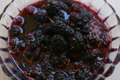 Glass bowl of sweet black mulberry jam on table, closeup