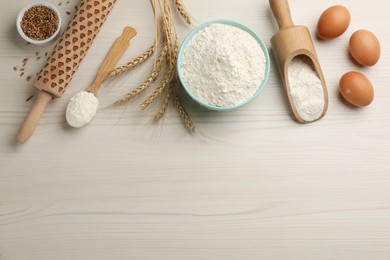 Flat lay composition with wheat flour and eggs on white wooden table. Space for text