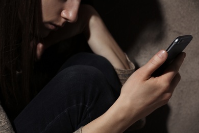 Photo of Woman using smartphone in dark room, closeup. Loneliness concept