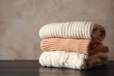 Photo of Stack of folded knitted sweaters on table. Space for text