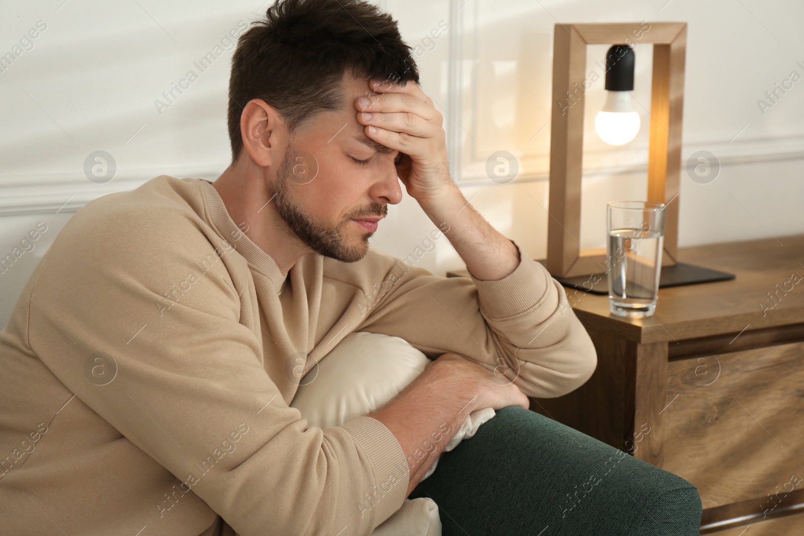 Photo of Man suffering from terrible migraine on sofa at home