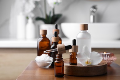 Photo of Essential oils, orchid flower and sea salt on wooden table in bathroom