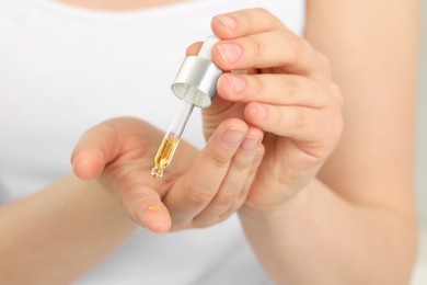 Photo of Woman applying essential oil onto hand, closeup