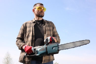 Photo of Man with modern saw against blue sky, low angle view