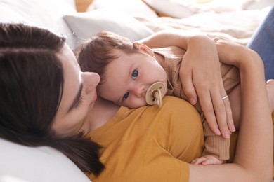 Photo of Happy young mother with her cute baby on bed at home, closeup