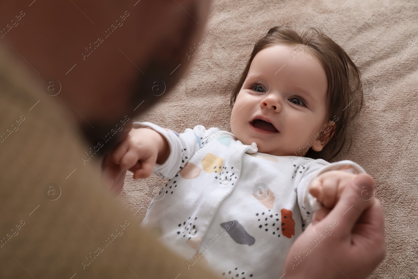 Photo of Father playing with his daughter on blanket, closeup